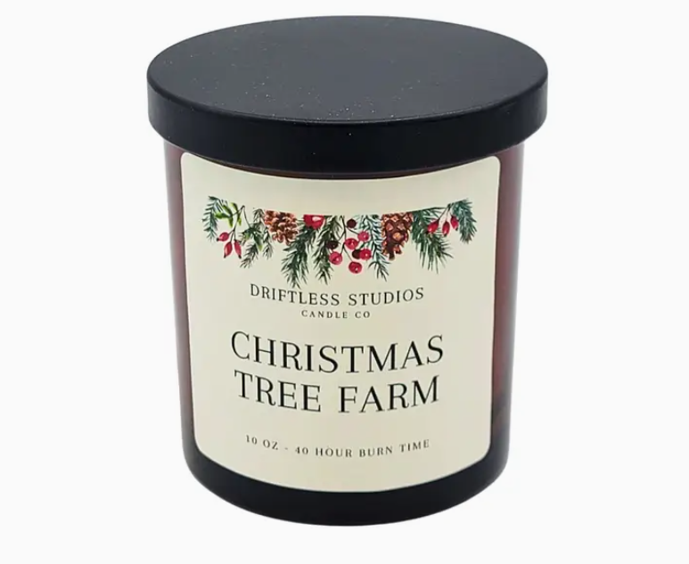 Candle with a label reading 'Christmas Tree Farm' from Driftless Studios Candle Co on a white background.