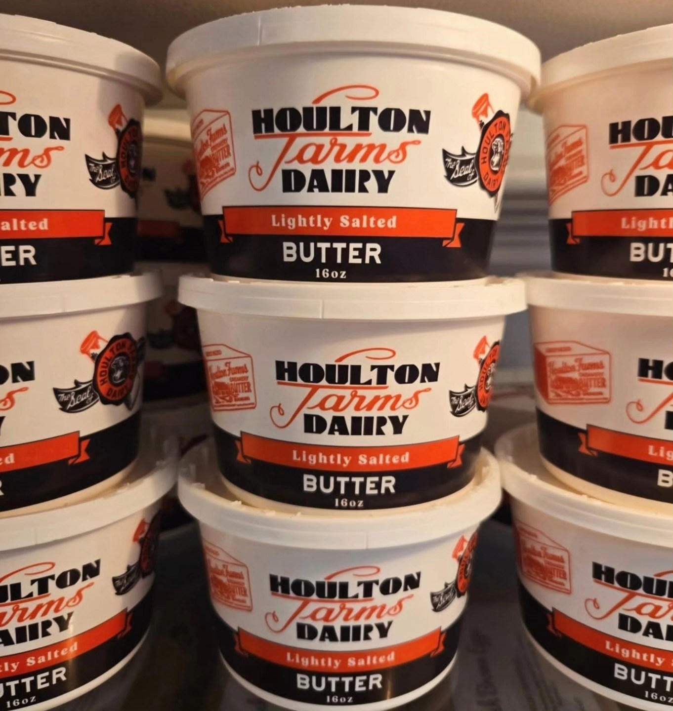 Tubs of Houlton Farms Dairy butter stacked on a refrigerator shelf.