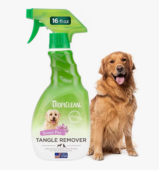 Green bottle of Tropiclean pet detangling spray with a golden retriever next to it on a white background.