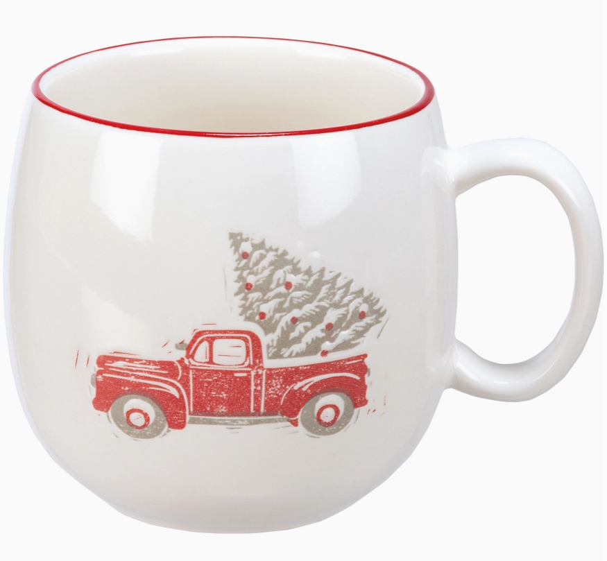 White coffee mug featuring design of a red truck carrying a Christmas tree, on a white background.