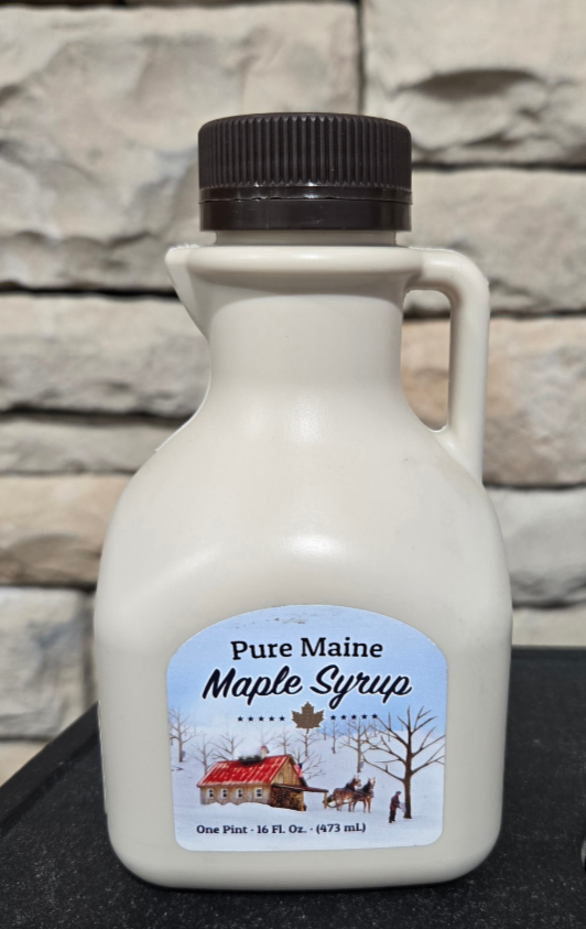 Bottle of Maine maple syrup with a label on a stone background.