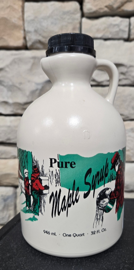 White maple syrup jug with colorful label against a stone wall background