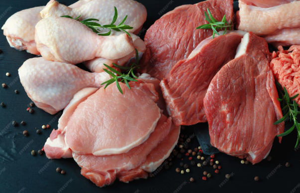 Raw chicken and beef pieces with rosemary on a dark surface