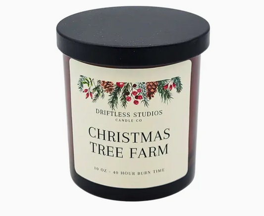 Candle with a label reading 'Christmas Tree Farm' from Driftless Studios Candle Co on a white background.