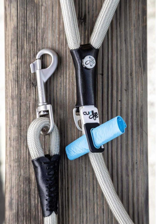 Dog leash with metal clip and blue poop bag on a wooden background