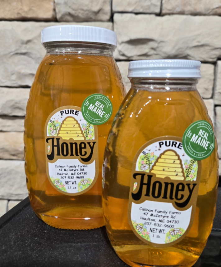Two jars of honey with labels on a stone surface