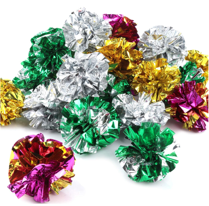 Colorful crumpled foil balls in green, gold, silver, and pink on a white background