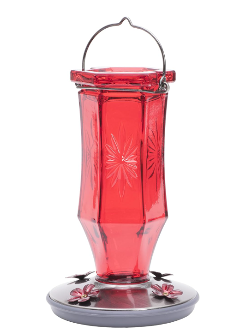 Red glass hummingbird feeder with starburst designs on a white background