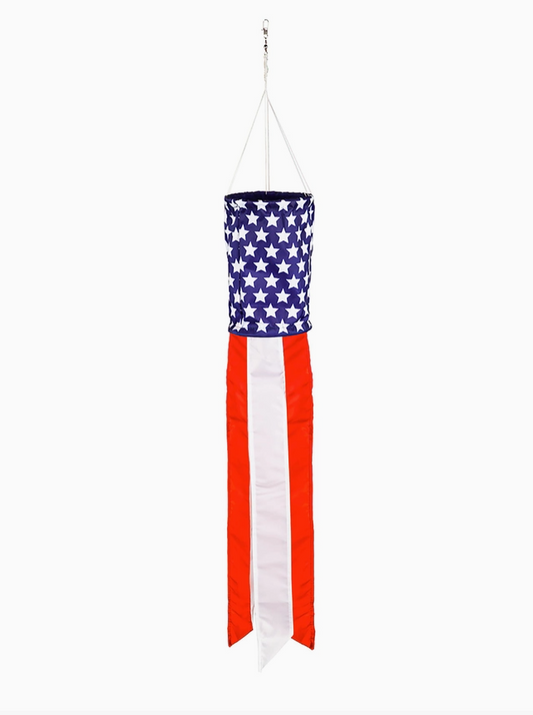 An American flag wind spinner hanging from a metal hook with white strings, featuring a blue section with white stars and red and white vertical stripes.