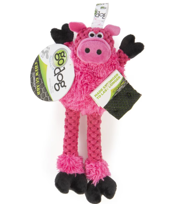 Pink pig-shaped dog toy with black hooves and tags on a white background