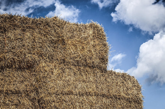 Stack of hay against a blue sky with clouds