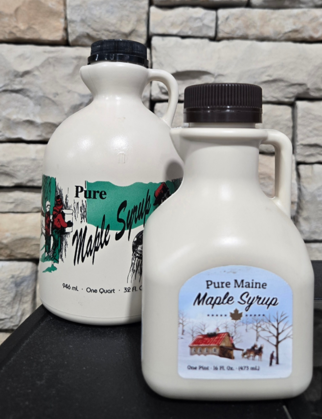Two bottles of Pure Maine Maple Syrup on a stone wall background with a stone wall.