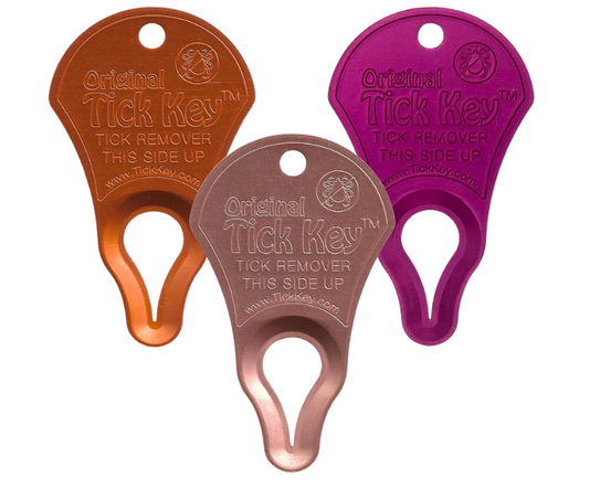 Three 'Original Tick Key' tick removers in orange, rose gold, and purple on a white background.