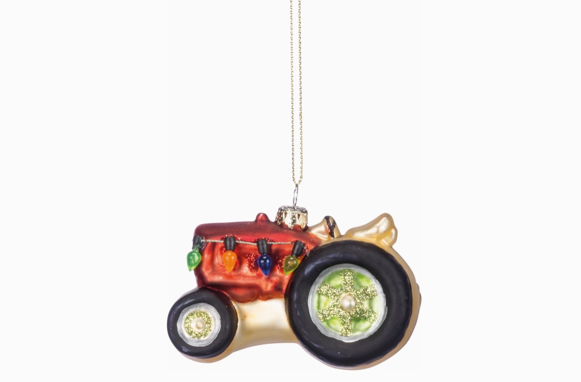 Glass tractor ornament with christmas lights on a white background.