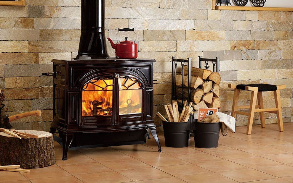 Wood-burning stove in a room with stone walls and wooden floors.